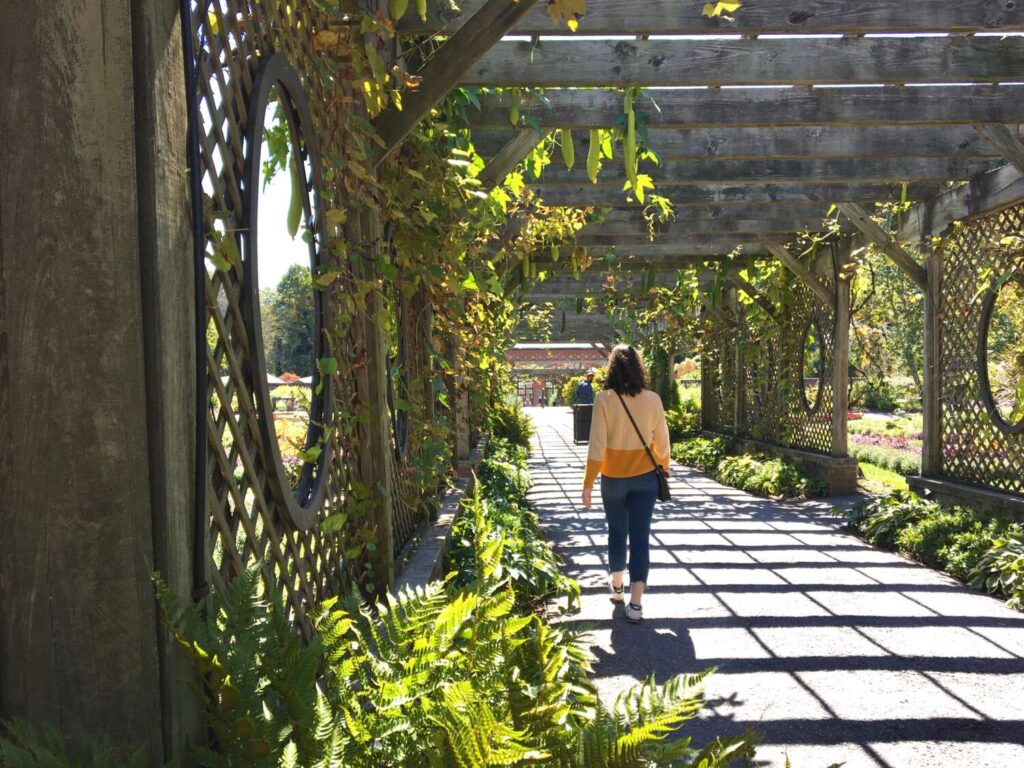 woman walking through a plant-filled garden